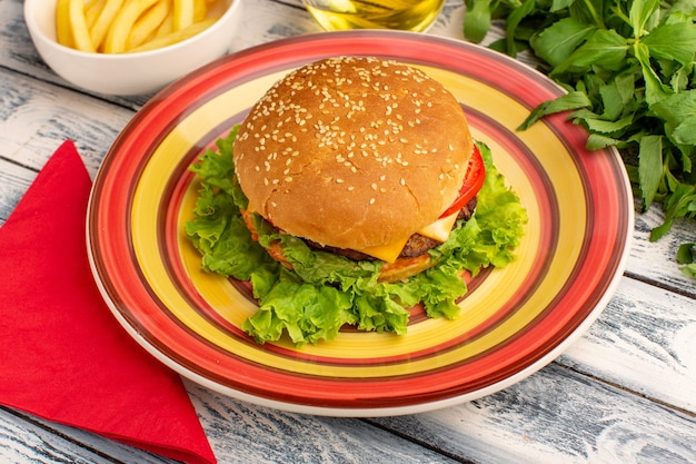 Leckeres Hühnchensandwich der Vorderansicht mit grünem Salat und Gemüse in farbigem Teller auf rustikalem grauem Schreibtisch.