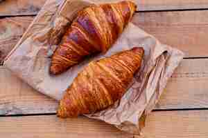 Kostenloses Foto leckeres knuspriges croissant auf einem holztisch. bild schließen