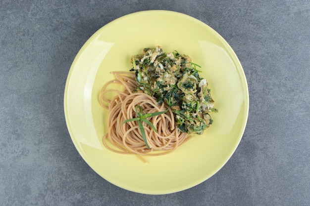 Leckeres omelett mit grüns und spaghetti auf gelbem teller. Kostenlose Fotos