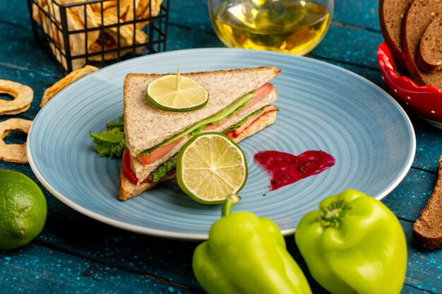 leckeres Sandwich in der blauen Platte zusammen mit grünen Paprika und Öl auf blau