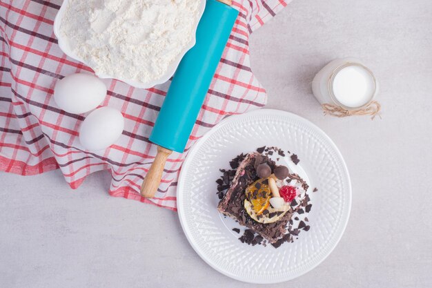 Leckeres Stück Kuchen mit Eiern, Milch und Mehl auf weißem Tisch.