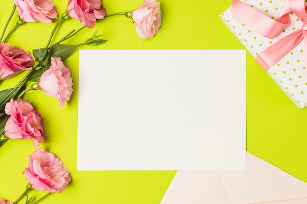 Leere Grußkarte; Geschenk und rosa Eustoma Blume über hellgrünem Hintergrund
