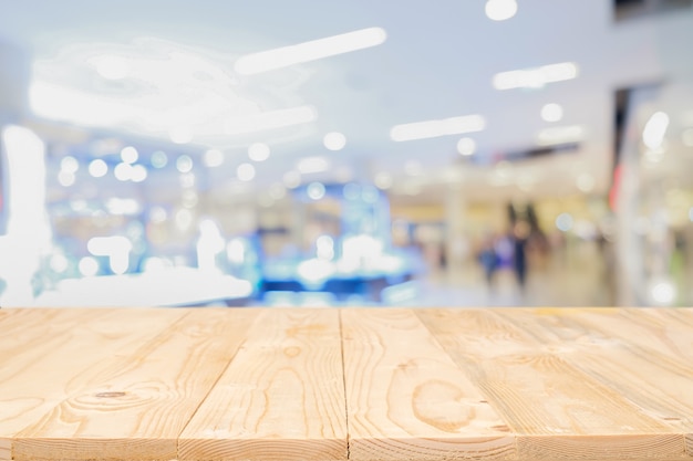 Leere Holztisch Platz Plattform mit verschwommenes Einkaufszentrum oder Einkaufszentrum Hintergrund für Produkt-Display Montage. Hölzerner Schreibtisch mit Kopie Raum.