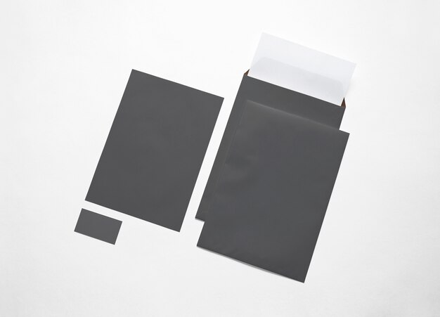 Leere schwarze Papierumschläge, Briefköpfe und Karte lokalisiert auf Weiß. 3D-Illustration.