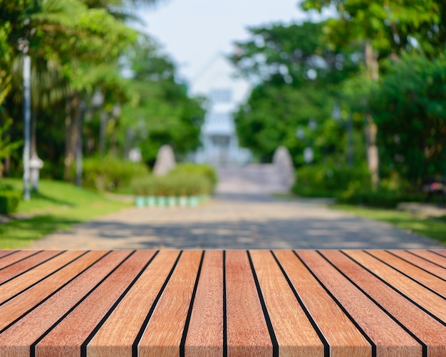 Leere Tabelle des hölzernen Brettes vor unscharfem Hintergrund. Braunes Holz der Perspektive mit unscharfen Leuteaktivitäten im Park - kann für Anzeige verwendet werden oder Ihre Produkte zusammenbauen. Frühling. Weinlese gefiltertes Bild.