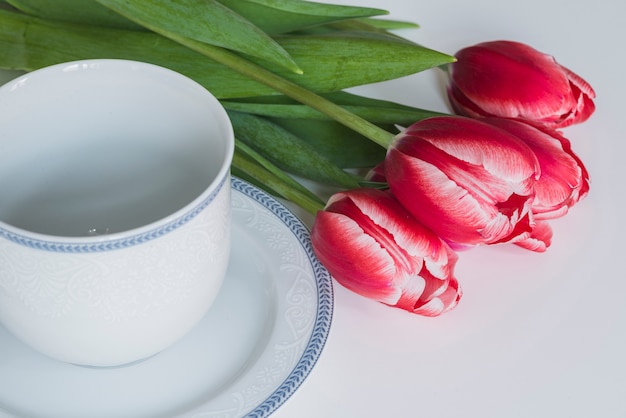 Leere Tasse neben dekorativen Tulpen für Muttertag