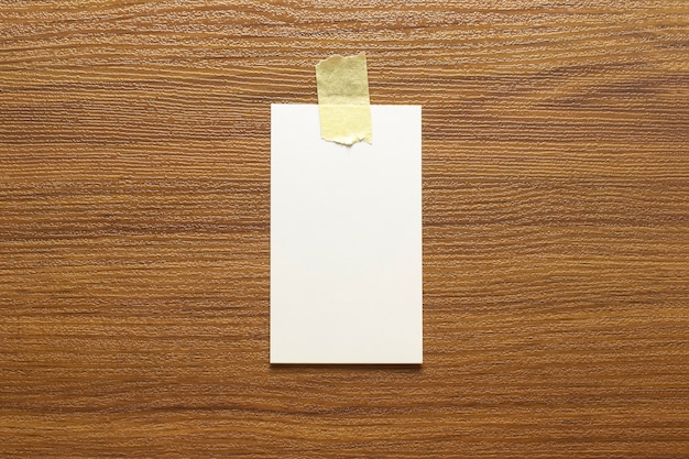 Leere Visitenkarten, geklebt mit gelbem Klebeband auf einer Holzoberfläche und freiem Platz, 3,5 x 2 Zoll groß