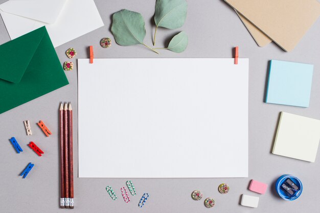 Leere weiße Seite mit dem Wäscheklammer umgeben mit Briefpapier auf grauem Hintergrund