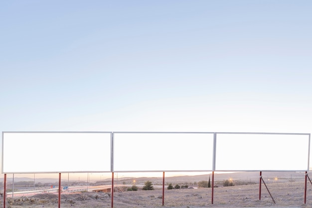 Kostenloses Foto leere werbungsanschlagtafeln nahe der landstraße gegen blauen himmel