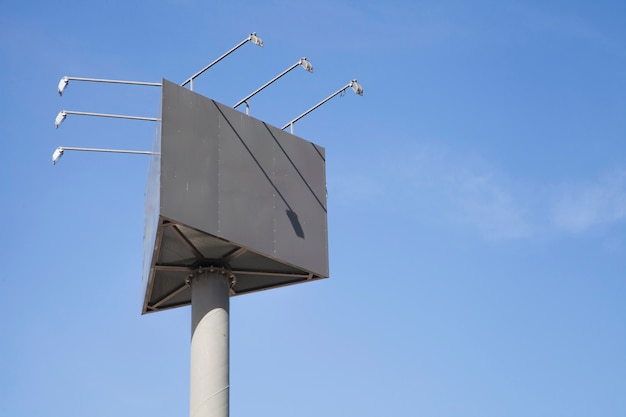 Leerer dreieckiger Anschlagtafelpfosten mit Lichtern gegen blauen Himmel