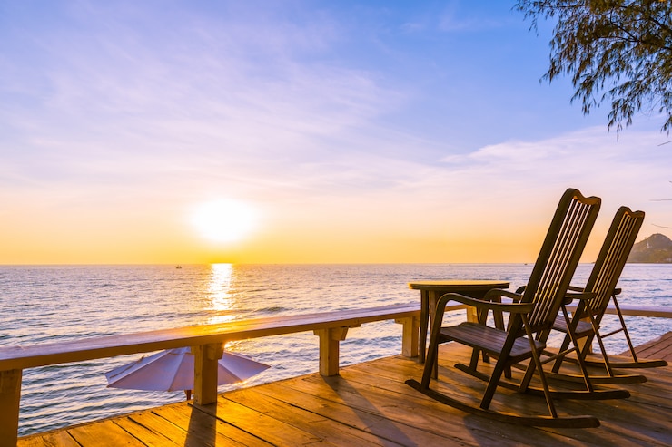 Kostenlose Foto leerer hölzerner stuhl und tabelle am patio am im freien mit schönem tropischem strand und meer