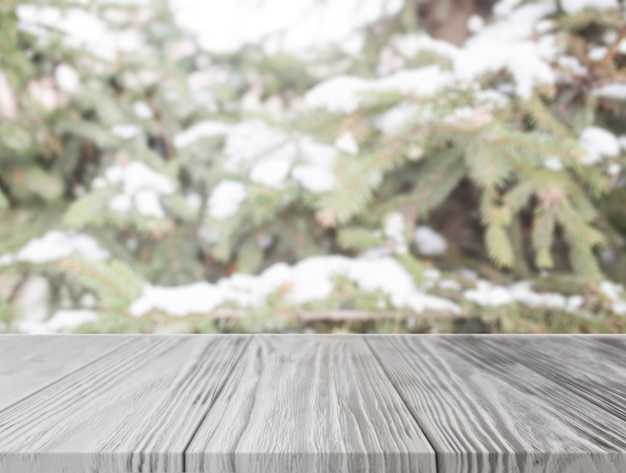 Leerer Holztisch vor Weihnachtsbaum mit Schnee