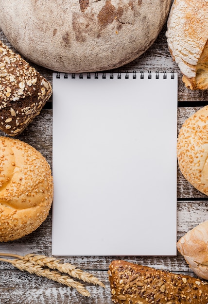 Kostenloses Foto leerer notizblock umgeben durch anordnung für brot