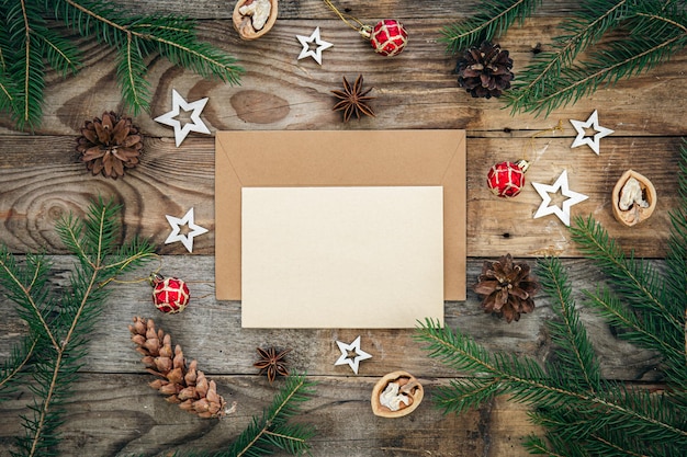 Leerer Papierumschlag und Weihnachtsdekor auf hölzernem Hintergrund kopieren Raum
