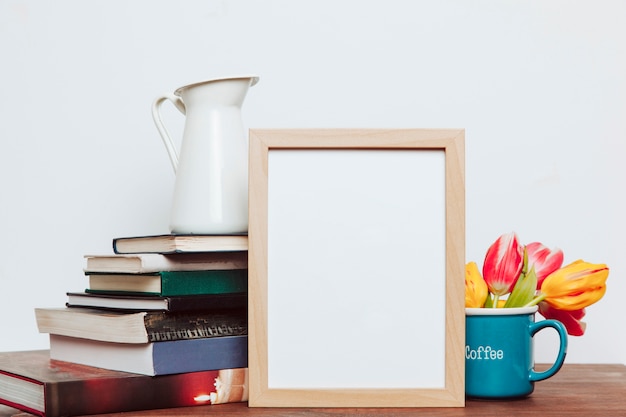 Leerer Rahmen zwischen Blumen und Büchern