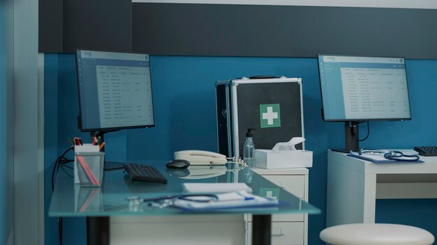 Leerer Schreibtisch in der Arztpraxis mit Computer und medizinischen Instrumenten. Niemand im Kabinett wurde für Beratungstermine und Kontrollbesuche verwendet, bei denen der Arzt Patienten mit Krankheiten behandelt.
