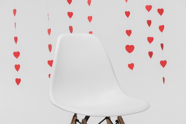 Leerer Stuhl der Nahaufnahme umgeben durch hängende Herzzahlen