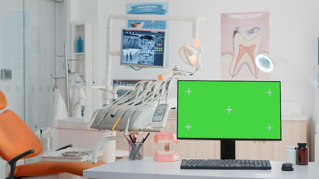 Leerer Zahnarztschrank mit horizontalem grünem Bildschirm auf dem Monitor. Niemand in der Zahnarztpraxis für zahnärztliche Versorgung mit isoliertem Hintergrund und Mockup-Vorlage auf dem Computer. Stomatologische Werkzeuge