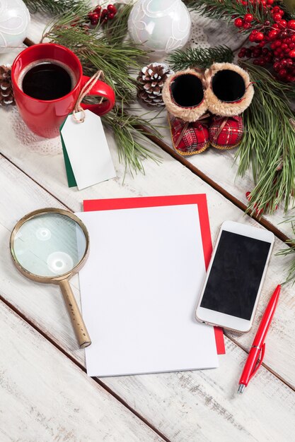 leeres Blatt Papier auf dem Holztisch mit einem Stift, Telefon und Weihnachtsdekorationen.