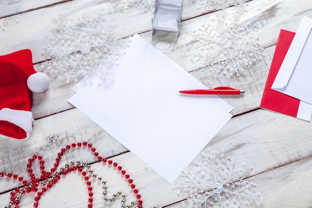 leeres Blatt Papier auf dem Holztisch mit einem Stift und Weihnachtsdekorationen.