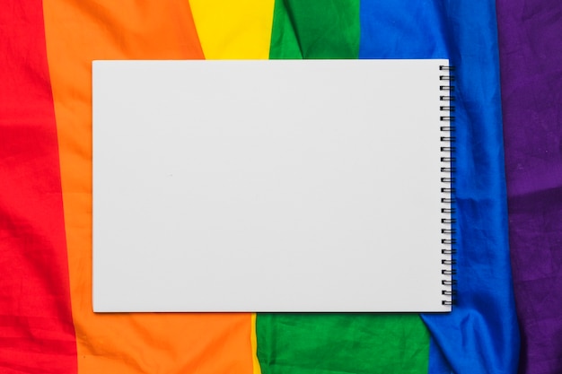 Kostenloses Foto leeres gewundenes notizbuch auf regenbogenflagge