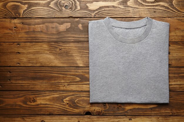 Leeres graues T-Shirt genau gefaltet auf rustikaler Holztischoberansicht