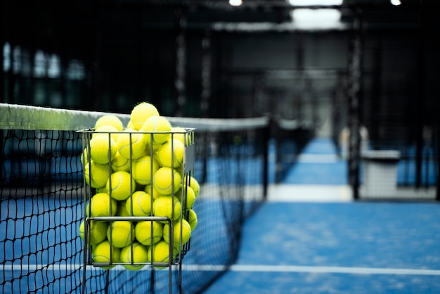 Leeres Paddle-Tennisfeld mit Bällen im Korb