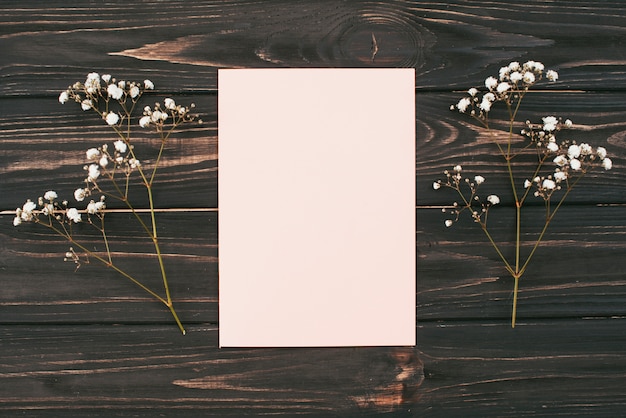 Kostenloses Foto leeres papier mit blumenniederlassungen auf tabelle