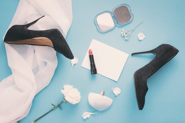 Leeres papier mit frauenschuhen und lippenstift auf tabelle