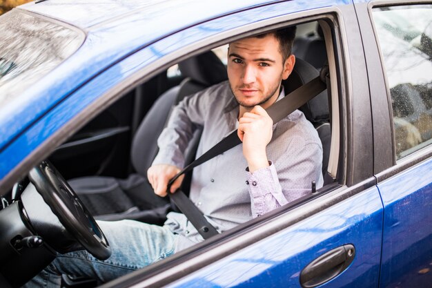 Legen Sie den Sicherheitsgurt an. Sicherheit des Sicherheitsgurts des jungen Mannes zuerst während der Fahrt