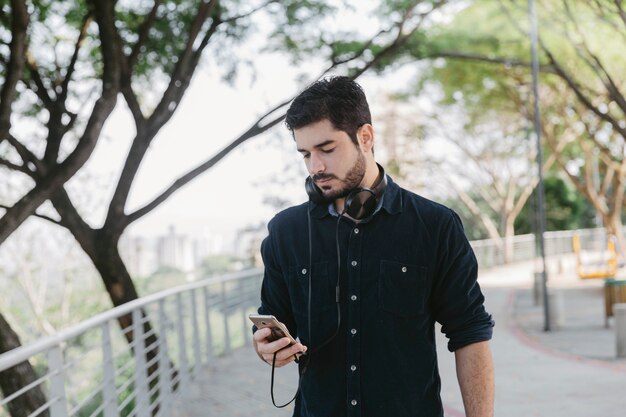 Legerer Mann mit Telefon und Kopfhörern