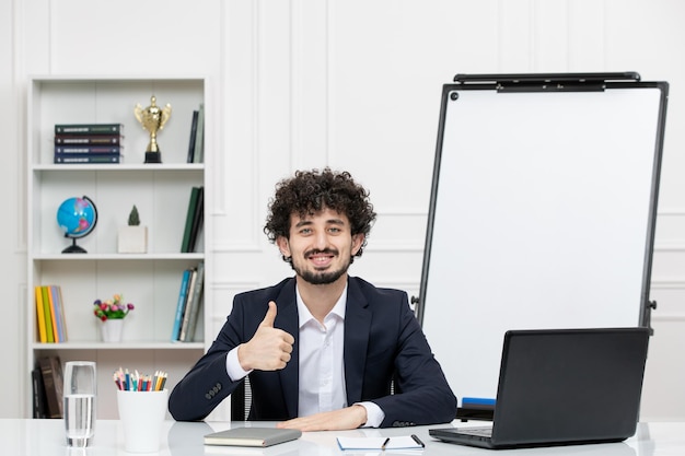 Lehrer brünette ausbilder mit computer im anzug und whiteboard im klassenzimmer zuversichtlich