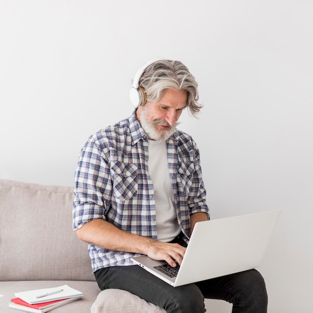 Kostenloses Foto lehrer, der auf der couch mit laptop bleibt