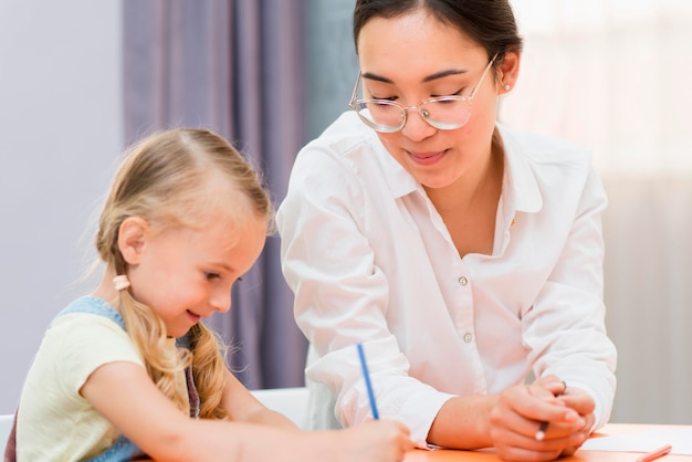 Lehrer hilft kleines Mädchen in der Klasse