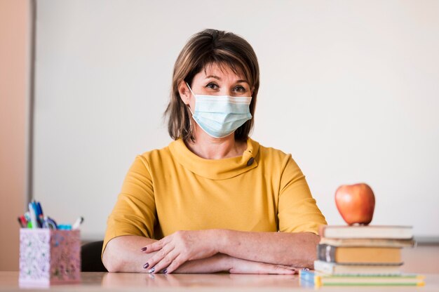 Lehrer mit Maske am Schreibtisch