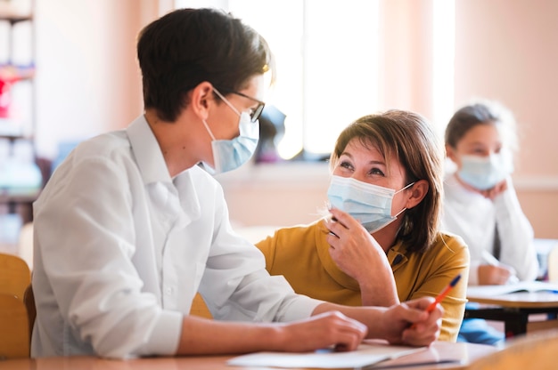 Lehrer mit Maske, die Klasse erklärt