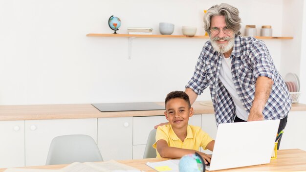 Lehrer sitzt neben Jungen am Laptop