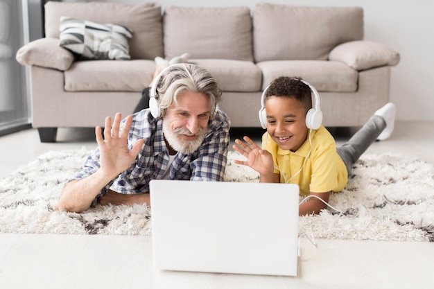 Kostenloses Foto lehrer und schüler sitzen auf dem boden und winken am laptop