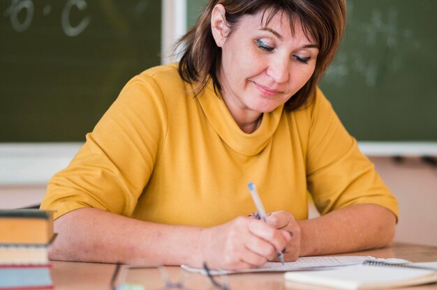 Lehrerin am Schreibtisch macht sich Notizen