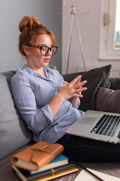 Lehrerin auf der Couch, die den Schülern während des Online-Unterrichts erklärt