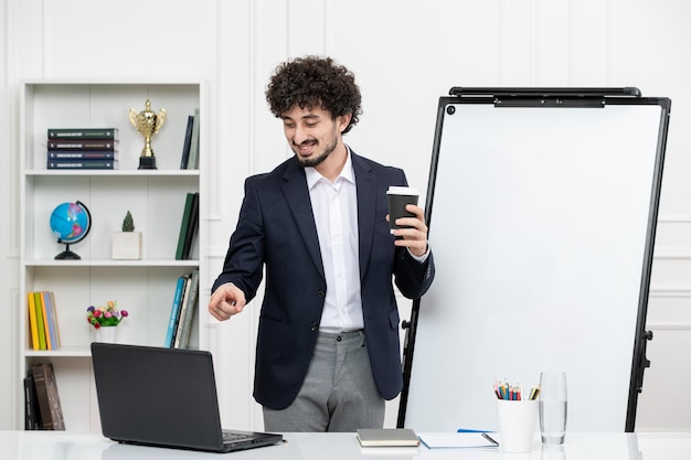 Lehrerin, brünette Ausbilderin mit Computer im Anzug und Whiteboard im Klassenzimmer, die vor der Kamera spricht