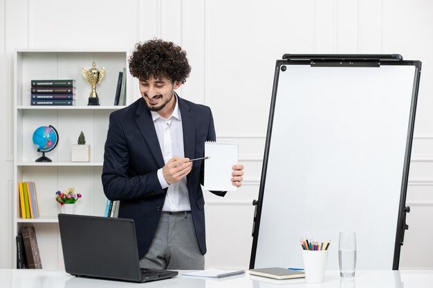 Lehrerin, brünette Ausbilderin mit Computer im Anzug und Whiteboard im Klassenzimmer, lächelnd mit Notizen