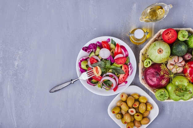 Leichter Salat mit Gemüse und Kräutern, serviert mit grünen Oliven.