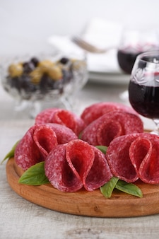 Leichter snack aus salami in blütenform gefaltet mit einem glas sherry Premium Fotos
