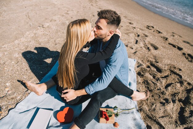 Leidenschaftliche Paare, die auf Strand küssen