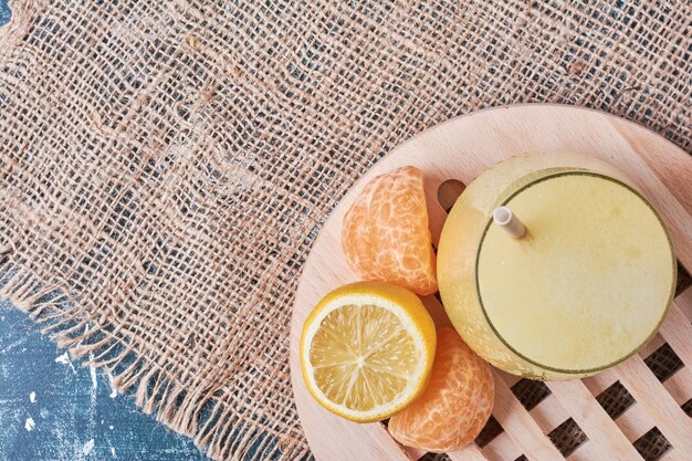 Lemonnd mandarinen mit einer tasse getränk auf blau.