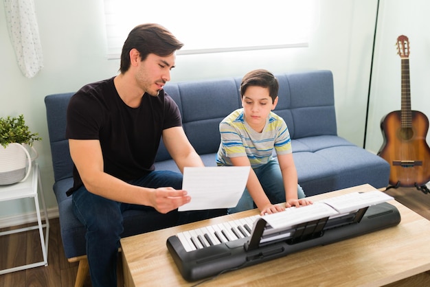 Lernen, ein neues Lied auf dem Klavier zu spielen. Künstlerischer kleiner Junge im Gespräch mit seinem Musiklehrer während einer Privatstunde