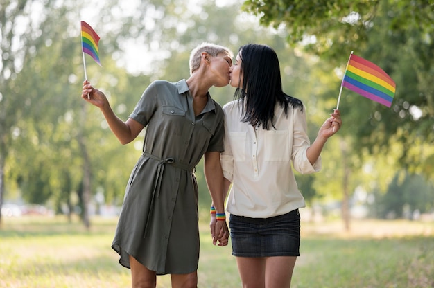 Lesbenpaar, das Flagge küsst und hält