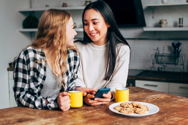 Lesbische Paare, die bei Tisch mit Smartphone sitzen