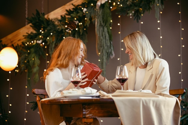 Lesbisches paar beim abendessen in einem restaurant. mädchen gibt ihrem schatz ein geschenk